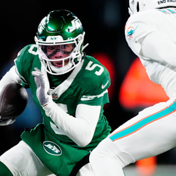 New York Jets wide receiver Garrett Wilson (5) runs with the ball as he tries to find a way past Miami Dolphins cornerback Jalen Ramsey (5), Sunday January 5, 2025, in East Rutherford.