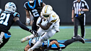 Nov 9, 2025; Charlotte, North Carolina, USA;  New Orleans Saints running back Alvin Kamara (41) with the ball as Carolina Panthers safety Nick Scott (21) and cornerback Mike Jackson (2) and linebacker Christian Rozeboom (56) defend in the fourth quarter at Bank of America Stadium. Mandatory Credit: Bob Donnan-Imagn Images