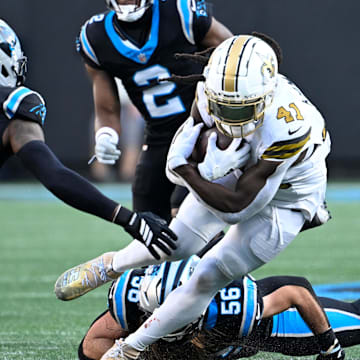 Nov 9, 2025; Charlotte, North Carolina, USA;  New Orleans Saints running back Alvin Kamara (41) with the ball as Carolina Panthers safety Nick Scott (21) and cornerback Mike Jackson (2) and linebacker Christian Rozeboom (56) defend in the fourth quarter at Bank of America Stadium. Mandatory Credit: Bob Donnan-Imagn Images
