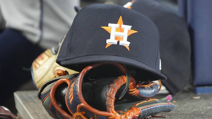 A detail view of a Houston Astros hat and ball glove in the dugout