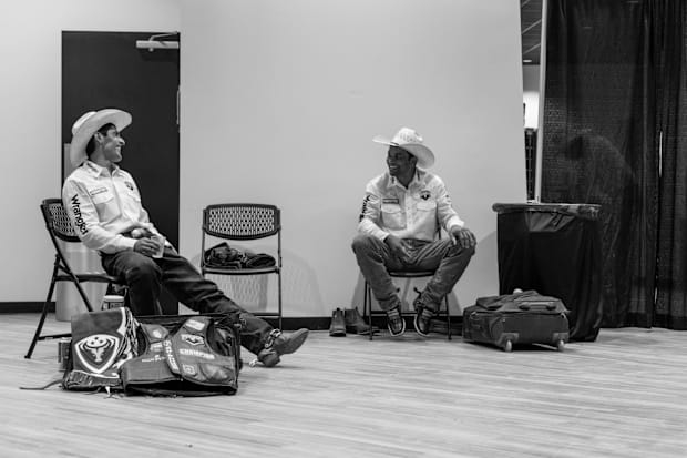 Two cowboys sitting in chairs talking.