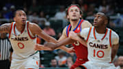 Jan 18, 2025; Coral Gables, Florida, USA; Southern Methodist Mustangs forward Matt Cross (33) looks for a rebound against Miami Hurricanes guard Paul Djobet (10) and guard Matthew Cleveland (0) during the second half at Watsco Center. Mandatory Credit: Sam Navarro-Imagn Images