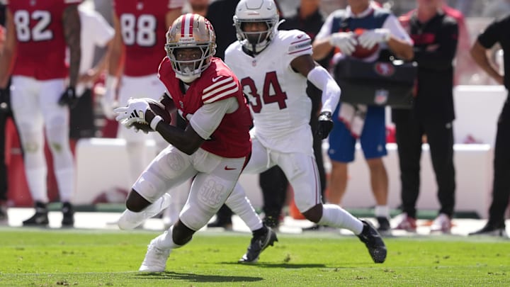 Oct 6, 2024; Santa Clara, California, USA; San Francisco 49ers wide receiver Brandon Aiyuk (left) runs after a catch against Arizona Cardinals safety Jalen Thompson (34) during the second quarter at Levi's Stadium. Mandatory Credit: Darren Yamashita-Imagn Images