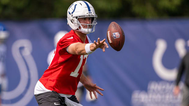 Colts quarterback Daniel Jones (red jersey) runs a play during an offseason practice.
