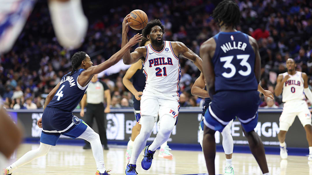 Oct 17, 2025; Philadelphia, Pennsylvania, USA; Philadelphia 76ers center Joel Embiid (21) drives the lane between Minnesota Timberwolves guard Rob Dillingham (4) and forward Leonard Miller (33) during the third quarter at Xfinity Mobile Arena. Mandatory Credit: Bill Streicher-Imagn Images