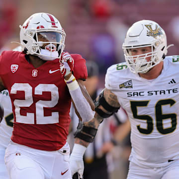 Sep 16, 2023; Stanford, California, USA; Stanford Cardinal running back E.J. Smith (22) runs with the ball past Sacramento State Hornets defensive lineman Brandon Knott (56) during the second quarter at Stanford Stadium. Mandatory Credit: Sergio Estrada-Imagn Images