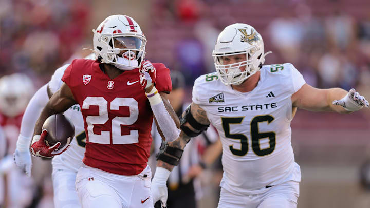 Sep 16, 2023; Stanford, California, USA; Stanford Cardinal running back E.J. Smith (22) runs with the ball past Sacramento State Hornets defensive lineman Brandon Knott (56) during the second quarter at Stanford Stadium. Mandatory Credit: Sergio Estrada-Imagn Images