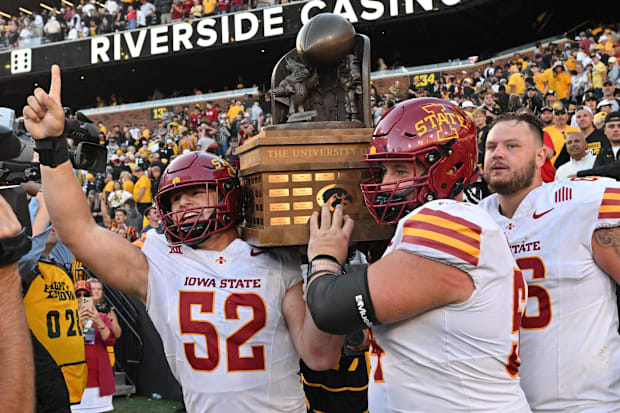 Cyclones defensive end Joey Petersen and offensive linemen Jarrod Hufford and Tyler Miller carry the Cy-Hawk trophy.