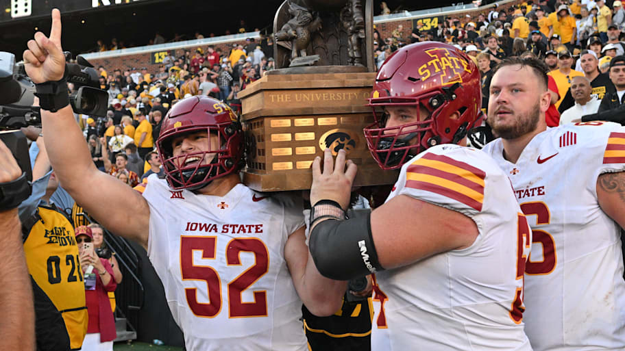 Cyclones defensive end Joey Petersen and offensive linemen Jarrod Hufford and Tyler Miller carry the Cy-Hawk trophy.