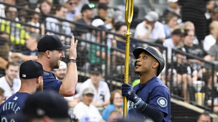 Seattle Mariners outfielder Luke Raley (left) hands second baseman Jorge Polanco (right) the trident after he hit a home run against the Chicago White Sox on Saturday.