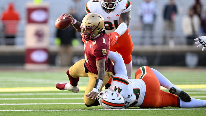 Nov 24, 2023; Chestnut Hill, Massachusetts, USA; Boston College Eagles quarterback Thomas Castellanos (1) is tackled by Miami Hurricanes defensive lineman Rueben Bain Jr. (44) and defensive lineman Jared Harrison-Hunte (81) during the second half at Alumni Stadium. Mandatory Credit: Brian Fluharty-USA TODAY Sports