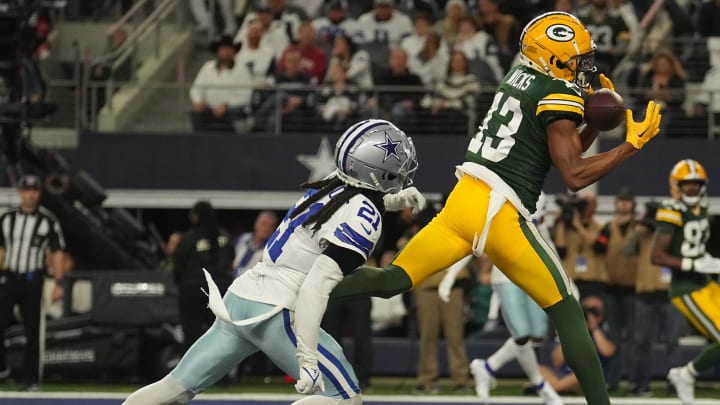 Green Bay Packers wide receiver Dontayvion Wicks (13) catches a touchdown pass while being covered by Dallas Cowboys cornerback Stephon Gilmore (21) during their playoff game.