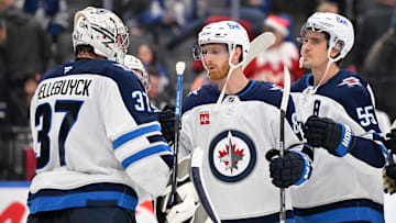Dec 23, 2024; Toronto, Ontario, CAN;  Winnipeg Jets goalie Connor Hellebuyck (37) is joined by forwards Kyle Connor (81) and Mark Scheifele (55) as they celebrate a win over the Toronto Maple Leaf at Scotiabank Arena. Mandatory Credit: Dan Hamilton-Imagn Images