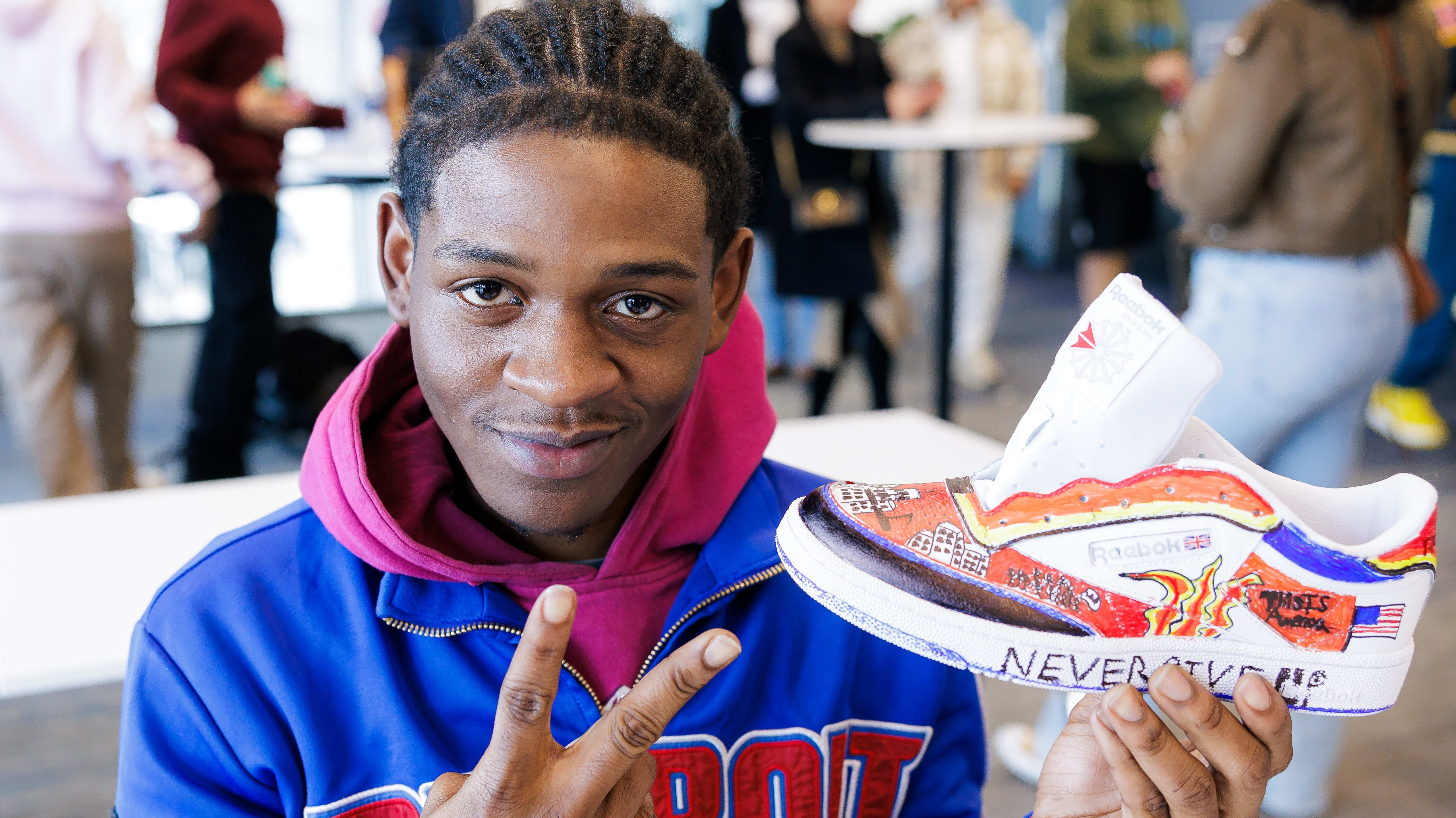 A student holds up his painted Reebok sneaker.