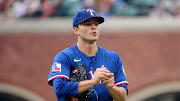 Texas Rangers starting pitcher Jack Leiter (35) rubs up a new baseball