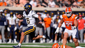West Virginia Mountaineers quarterback Garrett Greene (6) leaps past Oklahoma State Cowboys linebacker Gabe Brown (32) and nose tackle Justin Kirkland (97) on his way to the end zone to score a touchdown during a college football game between the Oklahoma State Cowboys (OSU) and the West Virginia Mountaineers at Boone Pickens Stadium in Stillwater, Okla., Saturday, Oct. 5, 2024.
