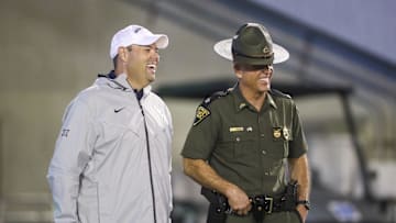 Sep 9, 2023; Morgantown, West Virginia, USA; West Virginia University Athletic Director Wren Baker talks to a West Virginia State Trooper during the third quarter against the Duquesne Dukes at Mountaineer Field at Milan Puskar Stadium. Mandatory Credit: Ben Queen-Imagn Images