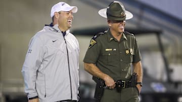 Sep 9, 2023; Morgantown, West Virginia, USA; West Virginia University Athletic Director Wren Baker talks to a West Virginia State Trooper during the third quarter against the Duquesne Dukes at Mountaineer Field at Milan Puskar Stadium. Mandatory Credit: Ben Queen-Imagn Images