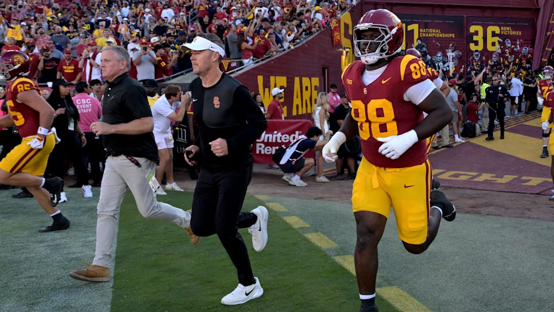 Oct 11, 2025; Los Angeles, California, USA; USC Trojans head coach Lincoln Riley, center, runs on to the field for the game against the Michigan Wolverines at United Airlines Field at the Los Angeles Memorial Coliseum. Mandatory Credit: Jayne Kamin-Oncea-Imagn Images