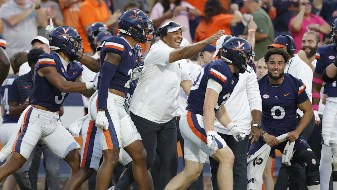 Oct 12, 2024; Charlottesville, Virginia, USA; Virginia Cavaliers head coach Tony Elliott (center) celebrates after Virginia Cavaliers safety Ethan Minter (30) intercepts the ball against the Louisville Cardinals during the second half at Scott Stadium. Mandatory Credit: Amber Searls-Imagn Images