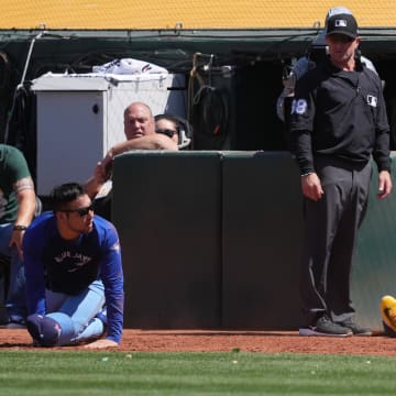 Toronto Blue Jays starting pitcher Yusei Kikuchi (left on ground) and Oakland Athletics first baseman Tyler Soderstrom (21) look at each other after colliding during a foul fly ball in the tenth inning at Oakland-Alameda County Coliseum on June 9.