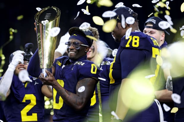 Michigan Wolverines football players hoist the national championship trophy after defeating Washington in the title game