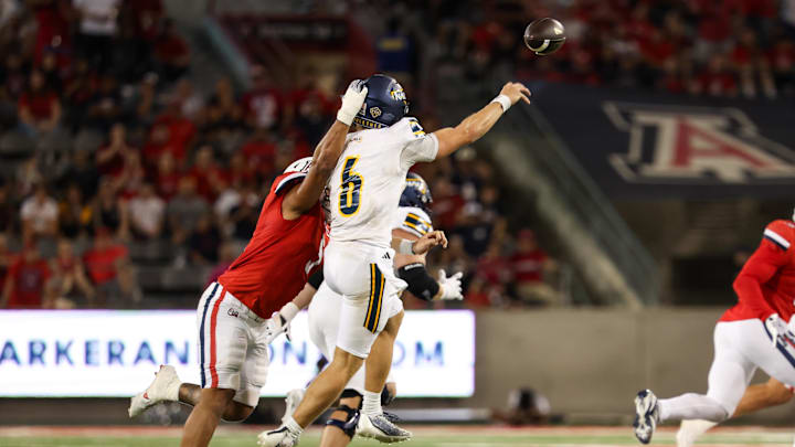 Sep 7, 2024; Tucson, Arizona, USA; Northern Arizona Lumberjacks quarterback Ty Pennington (6) gets rid of the ball while Arizona Wildcats linebacker Jacob Manu (5) goes in for the tackle during the fourth quarter at Arizona Stadium. Mandatory Credit: Aryanna Frank-Imagn Images