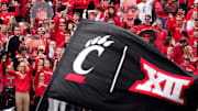 The Cincinnati Bearcats student section cheers on the team as a flag with the C-paw and Big 12 Conference logos is waved after a touchdown in the second quarter during a college football game between the Baylor Bears and the Cincinnati Bearcats, Saturday, Oct. 21, 2023, at Nippert Stadium in Cincinnati.