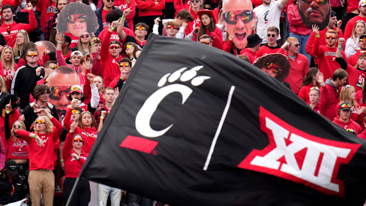 The Cincinnati Bearcats student section cheers on the team as a flag with the C-paw and Big 12 Conference logos is waved after a touchdown in the second quarter during a college football game between the Baylor Bears and the Cincinnati Bearcats, Saturday, Oct. 21, 2023, at Nippert Stadium in Cincinnati.