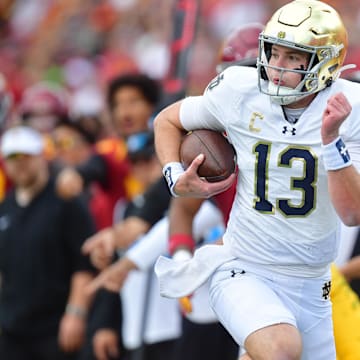 Nov 30, 2024; Los Angeles, California, USA; Notre Dame Fighting Irish quarterback Riley Leonard (13) runs the ball against the Southern California Trojans during the first half at the Los Angeles Memorial Coliseum. Mandatory Credit: Gary A. Vasquez-Imagn Images