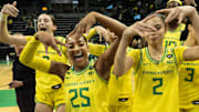 Oregon’s Elisa Mevius, left, Deja Kelly and Katie Fiso celebrate with teammates after defeating Washington at Matthew Knight Arena Wednesday, Feb. 12, 2025.
