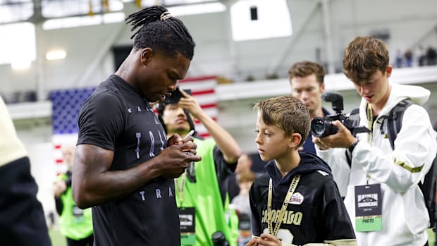 Apr 4, 2025; Boulder, CO, USA; Colorado Buffaloes wide receiver Travis Hunter (12) signs a trading card for a young fan after