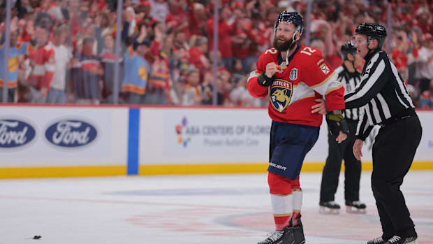 Hockey player is led off the ice by officia