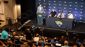 John Dever, Senior Vice President and Chief Communications Officer for the Jacksonville Jaguars, left, claps after introducing the Jacksonville Jaguars’ first-round pick, Colorado Buffaloes wide receiver and defensive back Travis Hunter, third from left, before answering questions during a press conference Friday, March 25, 2025 at Miller Electric Center in Jacksonville, Fla. with Head Coach Liam Coen, second from left and General Manager James Gladstone, right. [Doug Engle/Florida Times-Union]