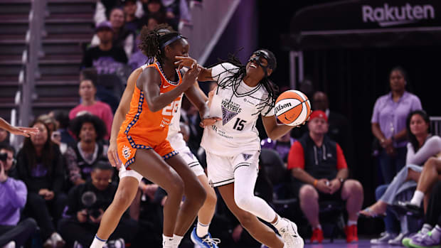 A female basketball player in an orange uniform guarding a player in a white uniforms with an orange and white basketball