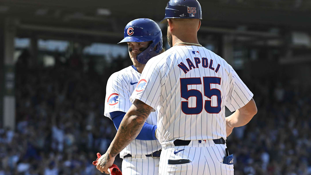 Jul 21, 2024; Chicago, Illinois, USA;  Chicago Cubs second baseman Nico Hoerner (2) is congratulated by first base coach Mike Napoli (55) after he was walked to beat the Arizona Diamondbacks in extra innings at Wrigley Field. 