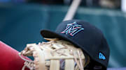 Apr 24, 2024; Atlanta, Georgia, USA; A detailed view of a Miami Marlins hat and glove in the dugout before a game against the Atlanta Braves at Truist Park. 