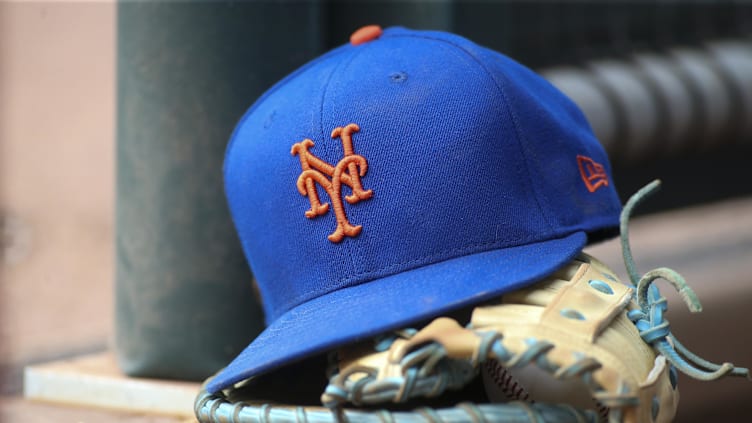 Jul 13, 2022; Atlanta, Georgia, USA; A detailed view of a New York Mets hat and glove in the dugout