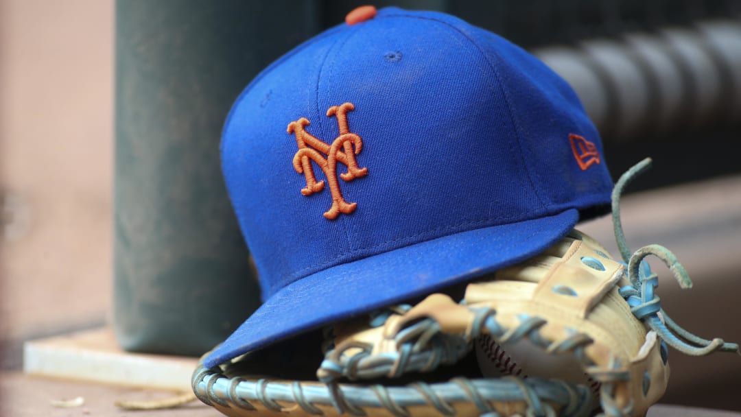 Jul 13, 2022; Atlanta, Georgia, USA; A detailed view of a New York Mets hat and glove in the dugout against the Atlanta Braves in the eighth inning at Truist Park.