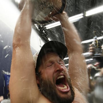 Los Angeles Dodgers pitcher Clayton Kershaw (22) celebrates in the clubhouse with the Commissioner's Trophy after defeating the Toronto Blue Jays in the 2025 MLB World Series at Rogers Centre on Saturday.