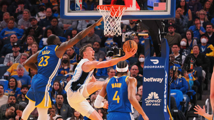 Orlando Magic small forward Franz Wagner shoots the ball between Golden State Warriors power forward Draymond Green and small forward Moses Moody.