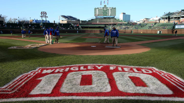 Apr 22, 2014; Chicago, IL, USA; A general view of a 100-year anniversary logo painted on the field as grounds crew members prepare the field before the game between the Chicago Cubs and Arizona Diamondbacks at Wrigley Field. 