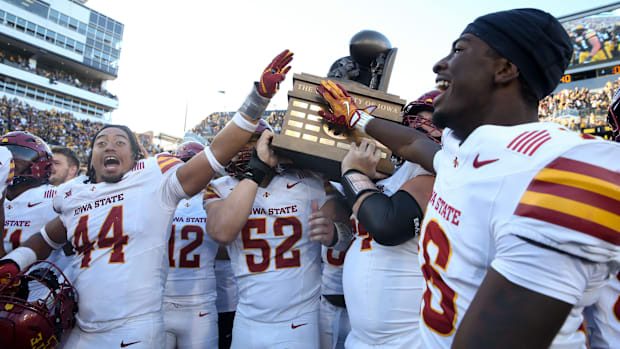 Iowa State players celebrate with the Cy-Hawk trophy after defeating Iowa 