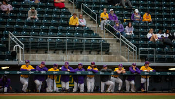 LSU Tigers line up along the dugout with a modest number of fans behind them. University of Oregon
