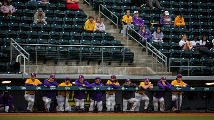 LSU Tigers line up along the dugout with a modest number of fans behind them. University of Oregon
