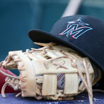 Apr 24, 2024; Atlanta, Georgia, USA; A detailed view of a Miami Marlins hat and glove in the dugout before a game against the Atlanta Braves at Truist Park. 