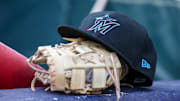 Apr 24, 2024; Atlanta, Georgia, USA; A detailed view of a Miami Marlins hat and glove in the dugout before a game against the Atlanta Braves at Truist Park. 