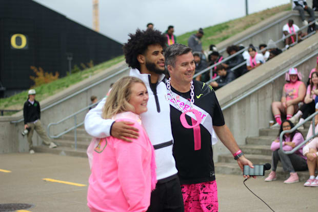 Oregon football quarterback Dante Moore poses with Men Wear Pink of Lane County ambassador James Conners and rally speaker Ap