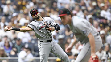 Sep 28, 2025; San Diego, California, USA; Arizona Diamondbacks third baseman Jordan Lawlar (10) throws over Brandon Pfaadt (32) as he tries to get the out on San Diego Padres right fielder Fernando Tatis Jr. (23) during the first inning at Petco Park. Mandatory Credit: Denis Poroy-Imagn Images