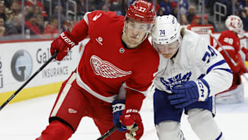 Dec 27, 2024; Detroit, Michigan, USA;  Detroit Red Wings defenseman Simon Edvinsson (77) and Toronto Maple Leafs center Bobby McMann (74) fight for position in the first period at Little Caesars Arena. Mandatory Credit: Rick Osentoski-Imagn Images